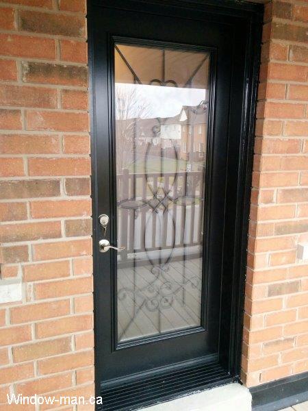 Front door. Single steel insulated front entry.  Black color. Black threshold bottom sill. Blackburn wrought iron glass insert